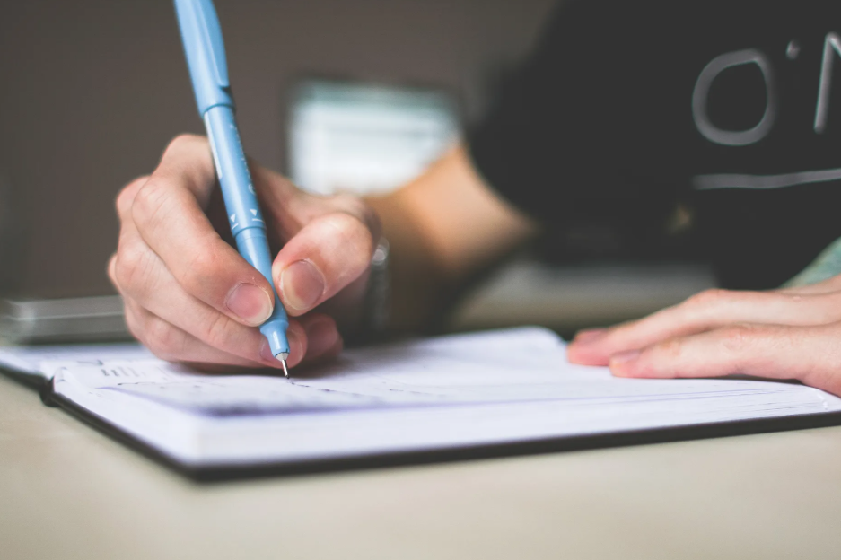 writing on a notebook using blue pen